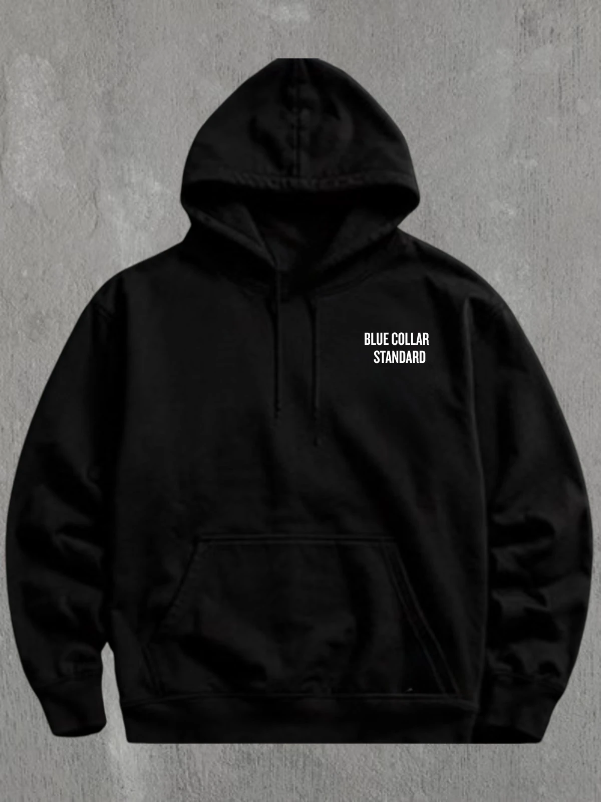 Blue Collar Standard heavyweight hoodie shot against a concrete workshop wall