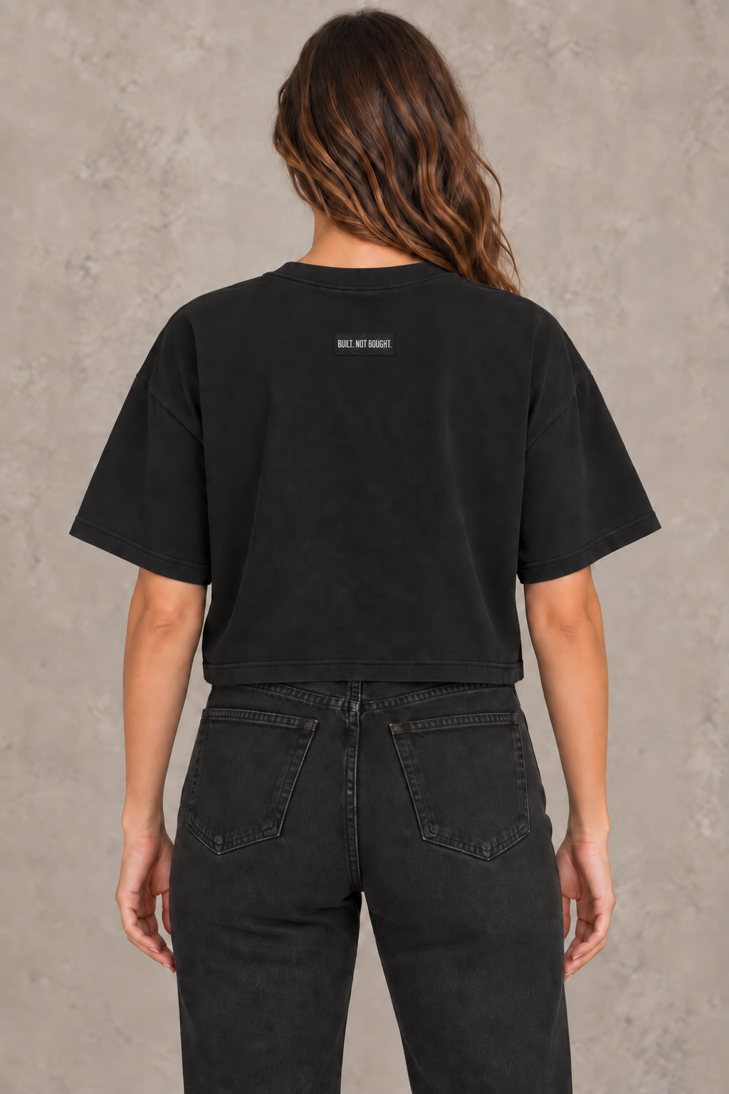 Woman wearing the black Standard Heavyweight Crop Tee, back view with Built. Not Bought. woven label