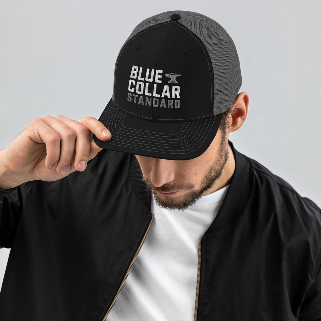 BCS Core Trucker Cap in black and charcoal - front view showing structured mid-profile crown and pre-curved visor